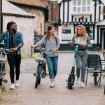 Three people walking with bikes in a town