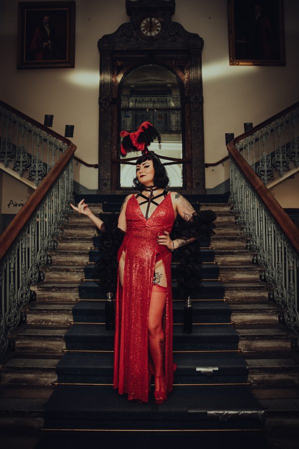 Big Band Burlesque dancer dressed in red on stairs