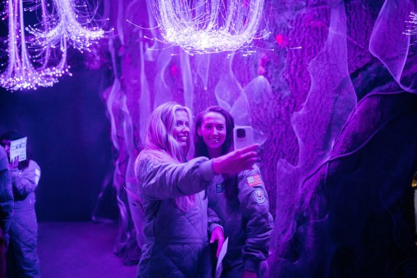 two women taking selfie in a purple lit background
